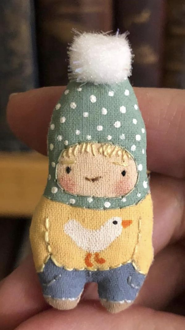 a hand holding a small doll wearing a hat