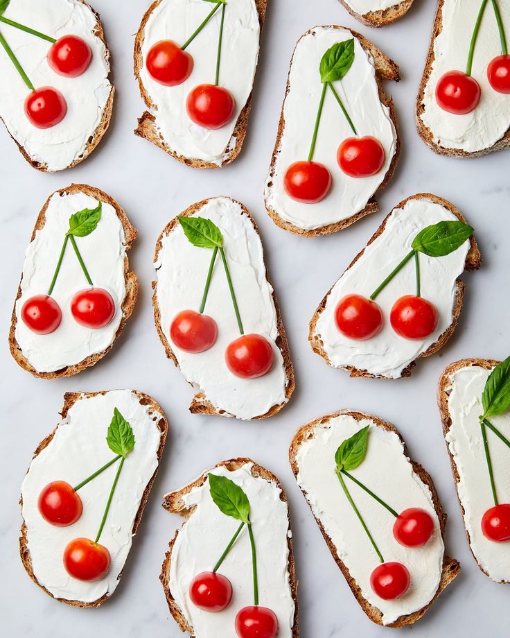 several pieces of bread with cream cheese and cherries on them, arranged in the shape of cherry tomatoes