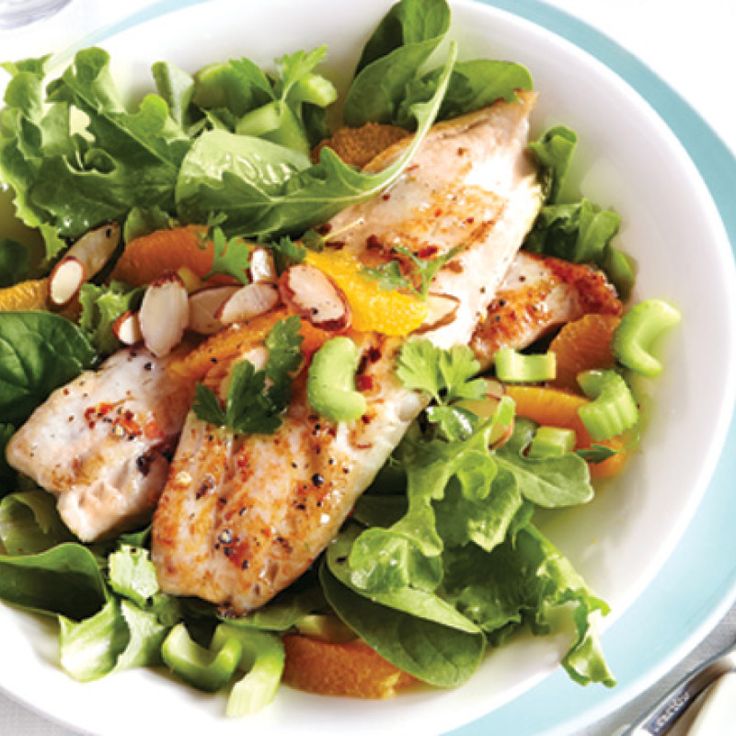 a white plate topped with chicken and vegetables next to a fork, knife and spoon