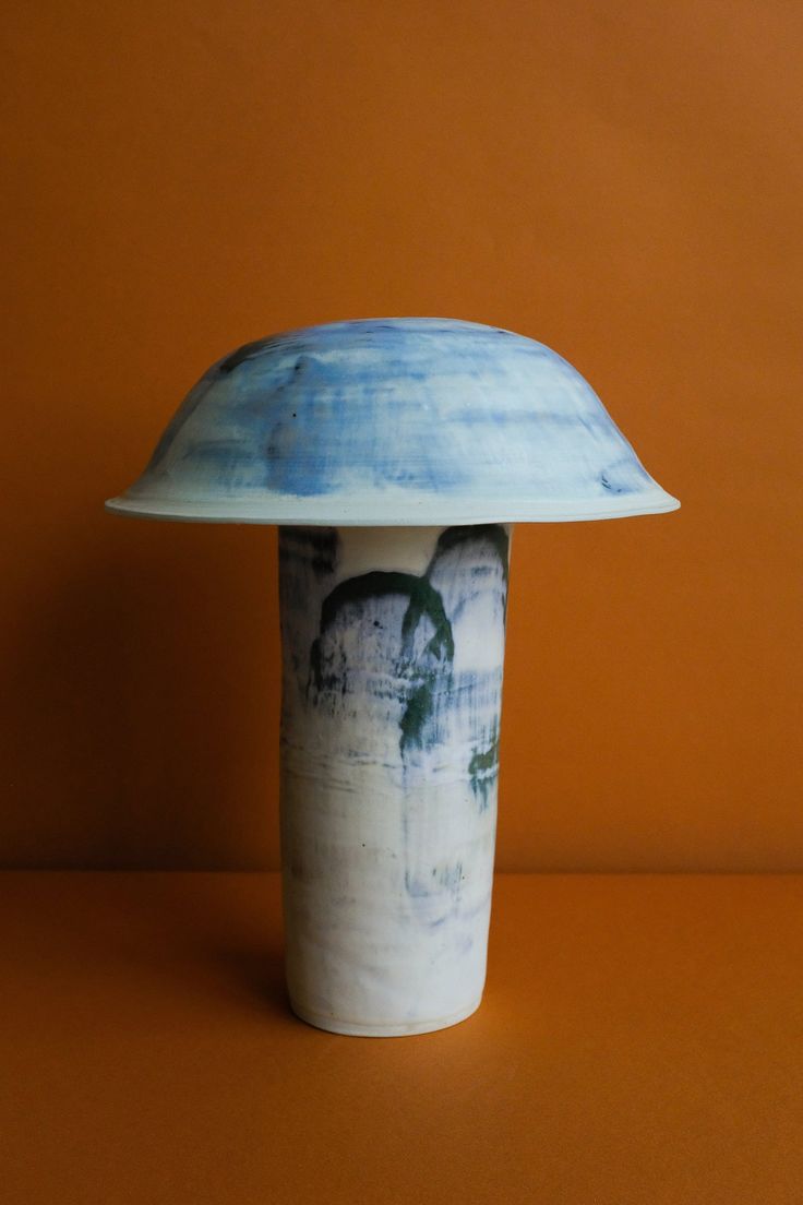 a blue and white vase sitting on top of a brown table next to an orange wall