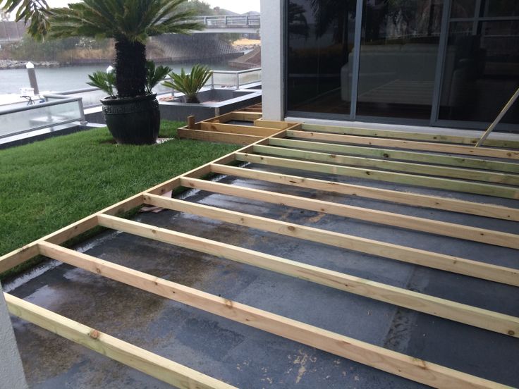 a wooden bed frame sitting on top of a lush green field