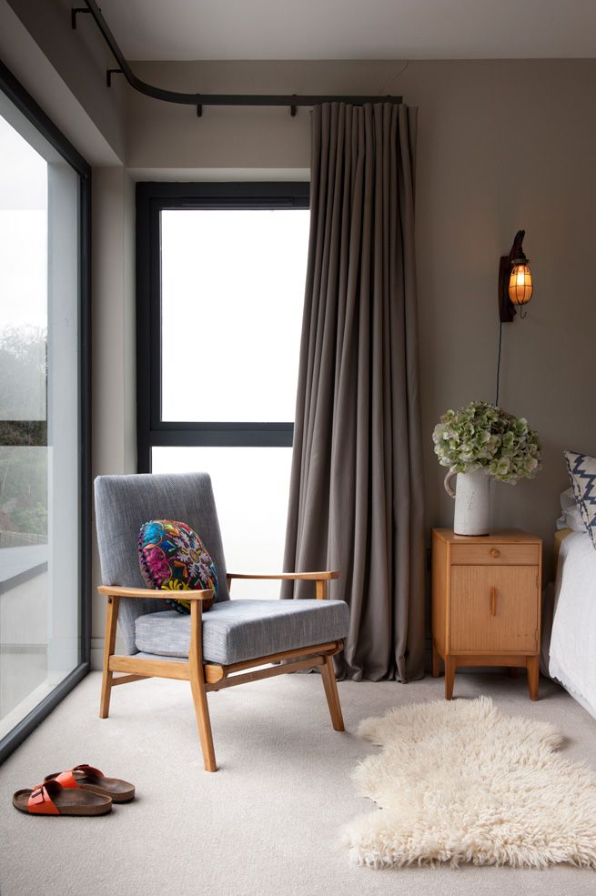 a bedroom with a large window and a chair in front of the bed that has a white rug on it