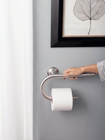 a person holding a roll of toilet paper in front of a wall with a leaf on it