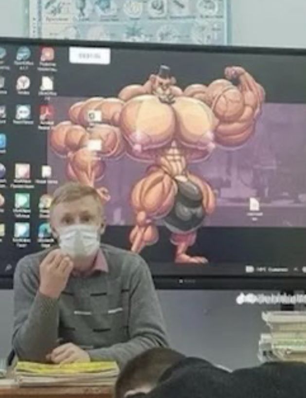 a man wearing a face mask sitting at a desk in front of a computer monitor