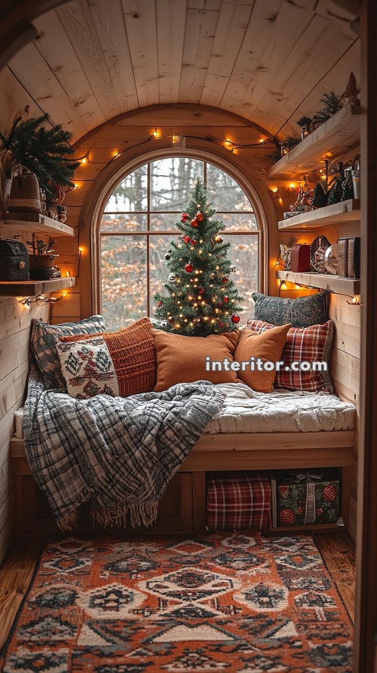 a christmas tree is in the corner of a window sill with pillows and blankets on it