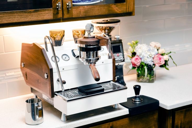 an espresso machine sitting on top of a counter next to a vase with flowers