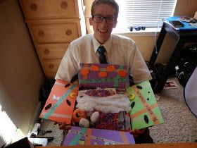 a man sitting on the floor holding up several boxes filled with crafting materials and decorations