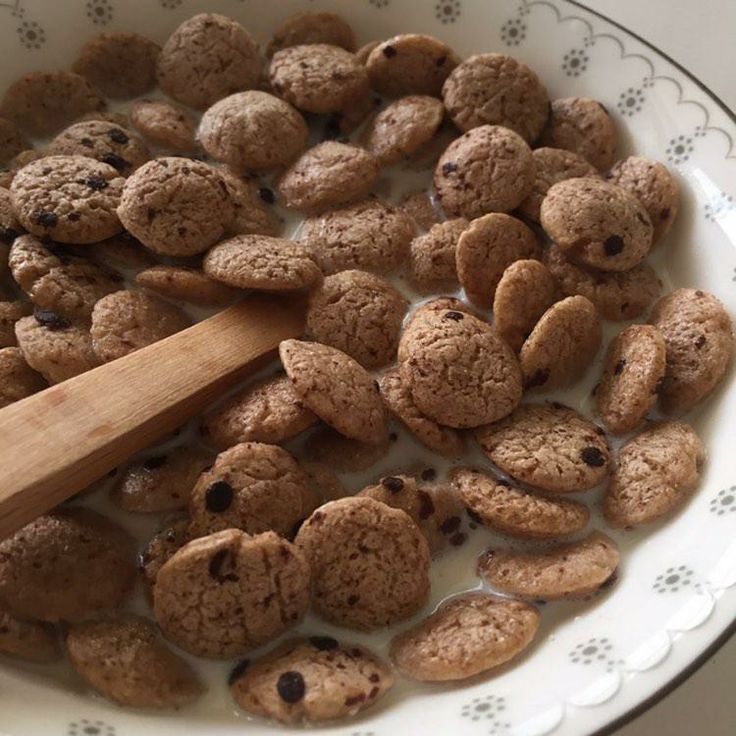 a bowl full of cookies and chocolate chips with a wooden spoon in the top left corner