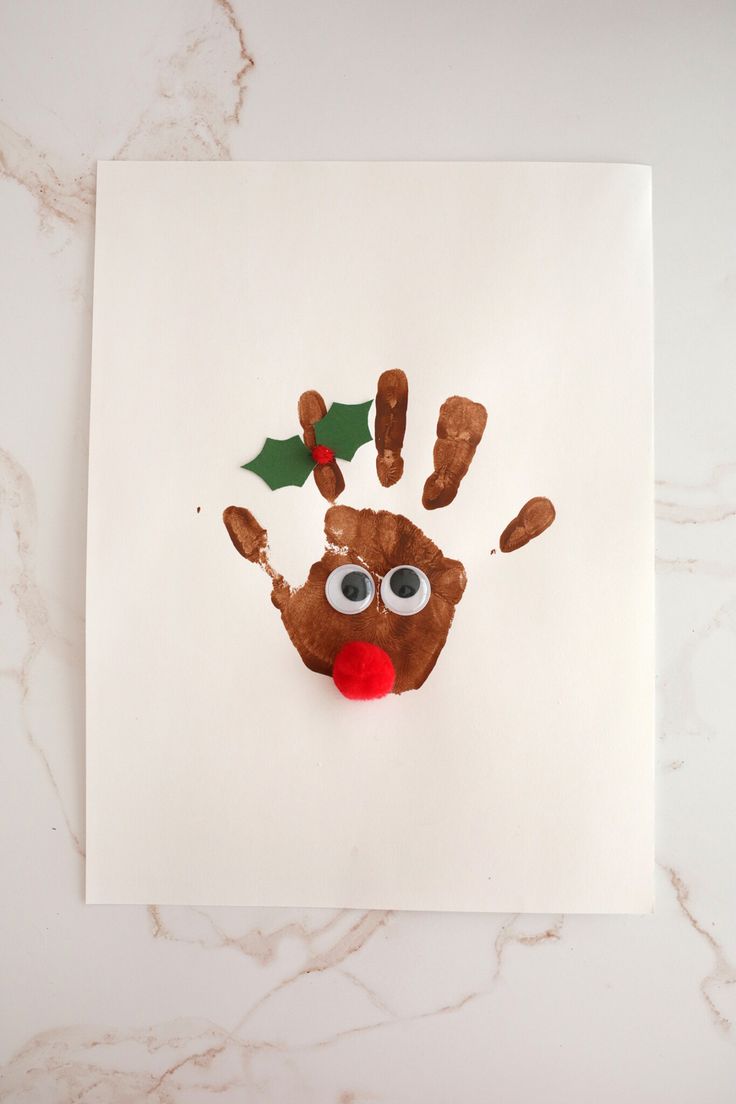 a handprint with a santa clause on it and holly decorations hanging from the top