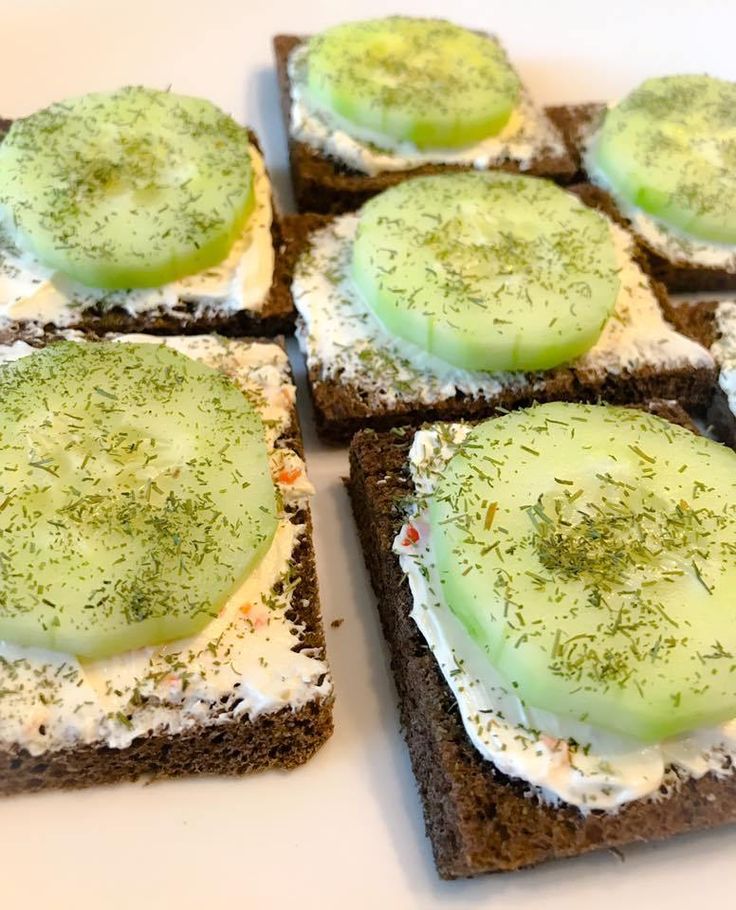 four pieces of bread topped with cucumber and cream on top of each other