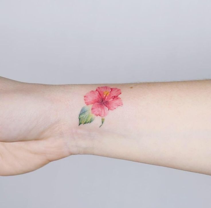 a woman's arm with a pink flower tattoo on the left side of her arm