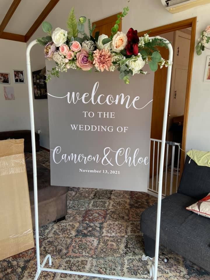 a welcome sign with flowers and greenery on it in front of a living room