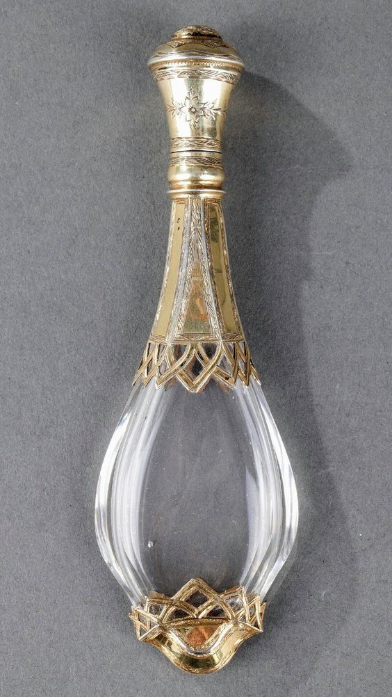 an ornate gold and clear glass bottle on a gray background