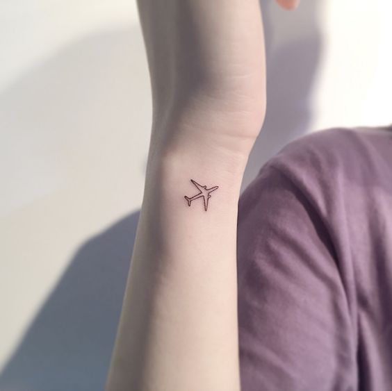 a small airplane tattoo on the left wrist is shown in front of a woman's arm