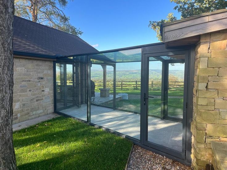 an enclosed patio with glass walls on the outside and grass in the front yard area