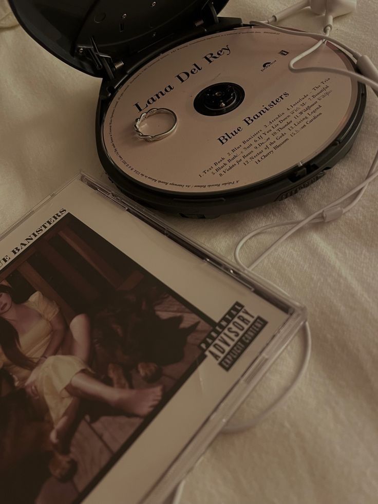 an open cd case sitting on top of a bed next to a white sheet covered table