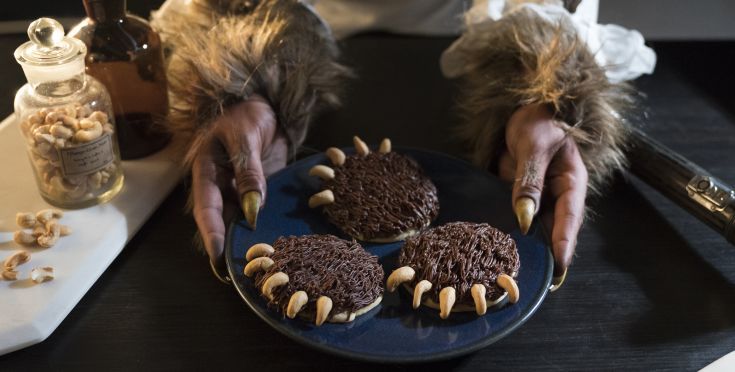 a person with claws on their hands holding some cookies in front of them and nuts