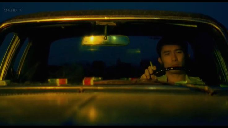 a man sitting in the back seat of a car holding a pipe to his mouth