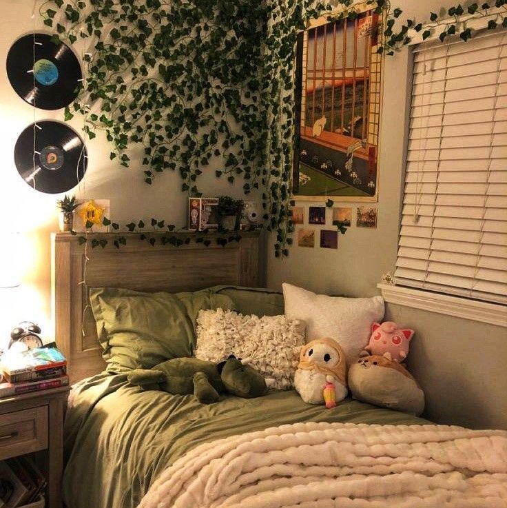 a bed with pillows and stuffed animals on it in a room decorated with green plants