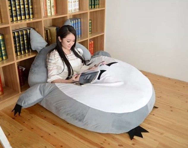 a woman is sitting on an inflatable bed with a bookcase behind her