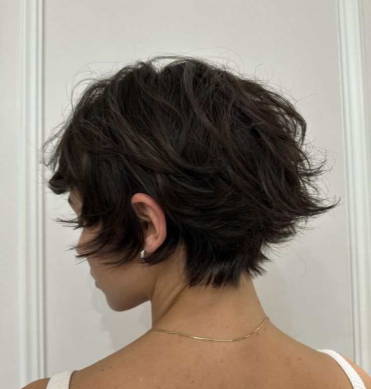 the back of a woman's head with short black hair in front of white door