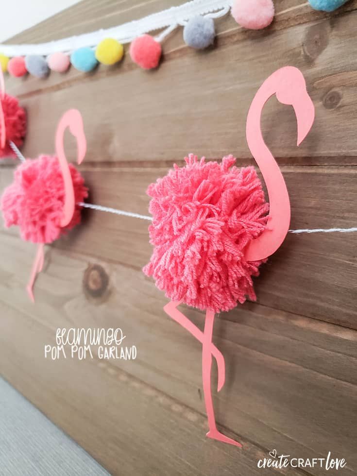 pink flamingo pom - pom garland hanging on wood planks