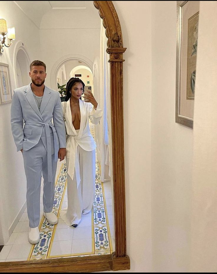 a man and woman standing in front of a mirror