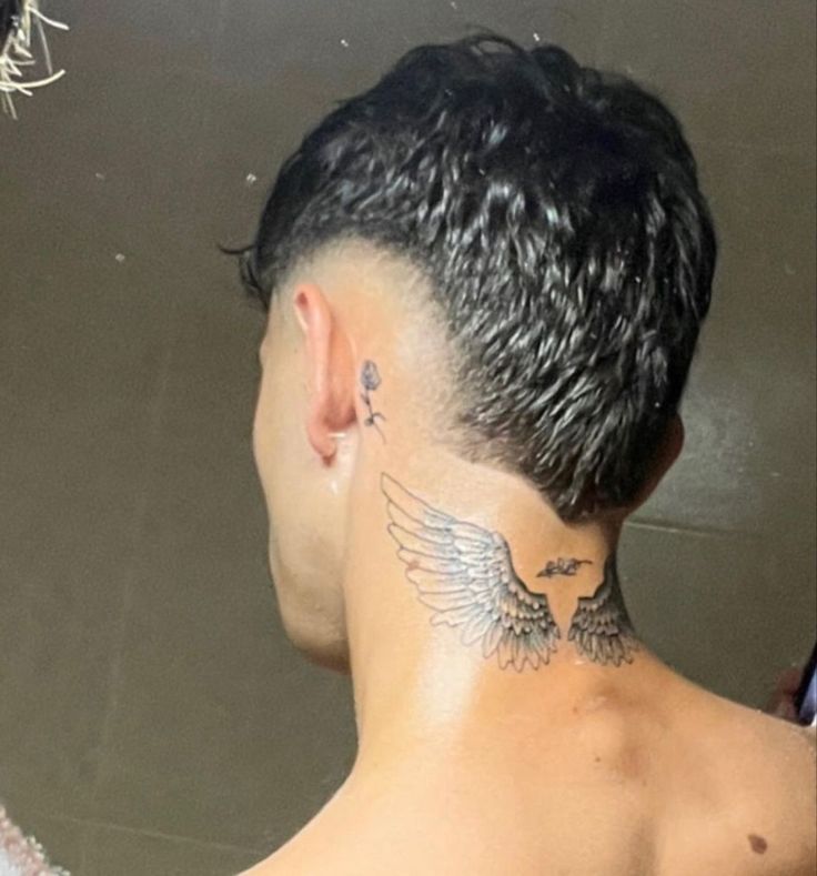 the back of a man's head with an eagle tattoo on his left side