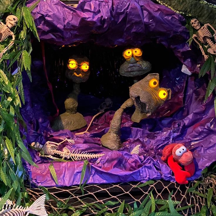 an outdoor halloween scene with fake skeletons and creepy eyes in the purple plastic tent, surrounded by green foliage