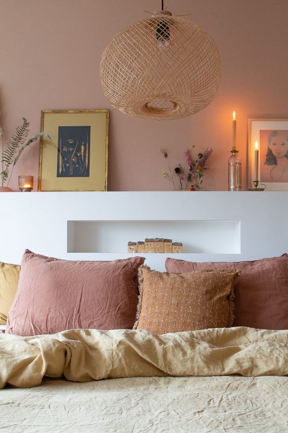 a bed with pillows and blankets on top of it in front of a wall filled with pictures