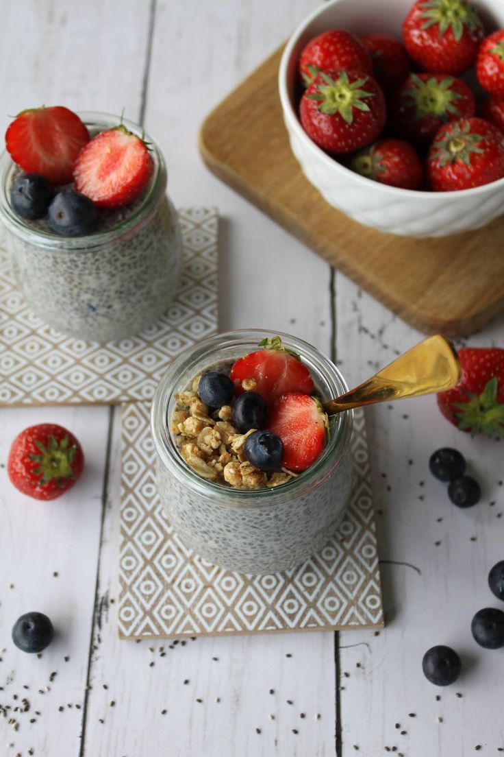 two jars filled with granola and strawberries