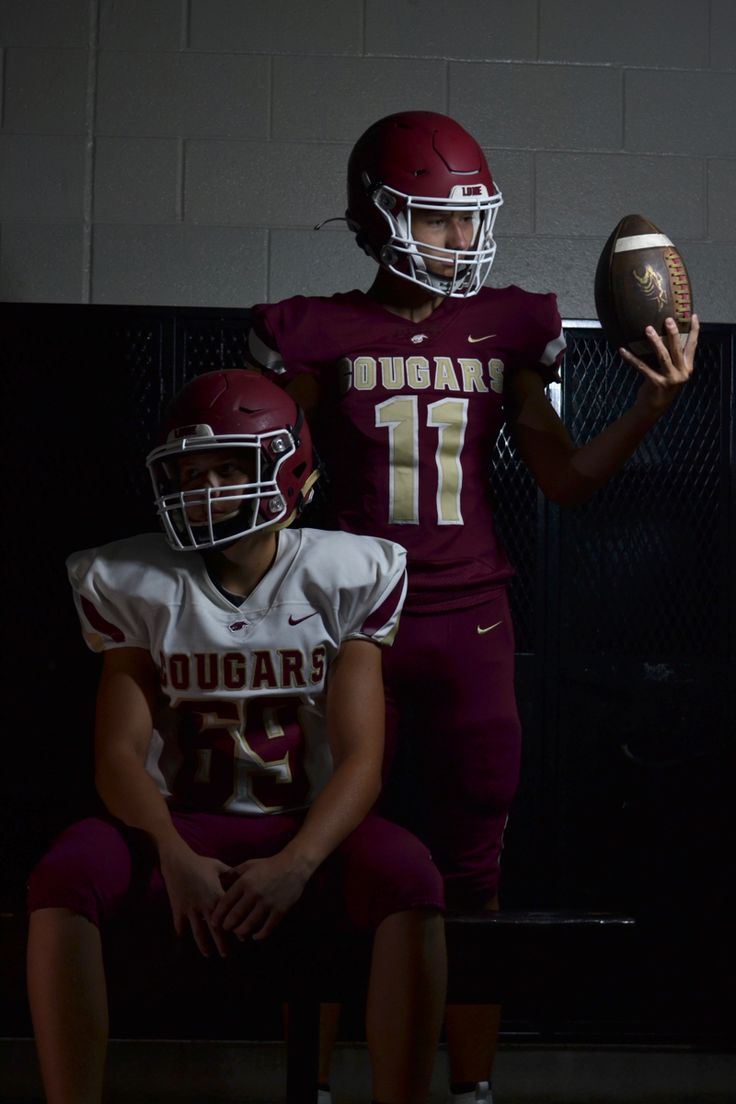 two football players are sitting on the bench and one is holding a ball in his hand