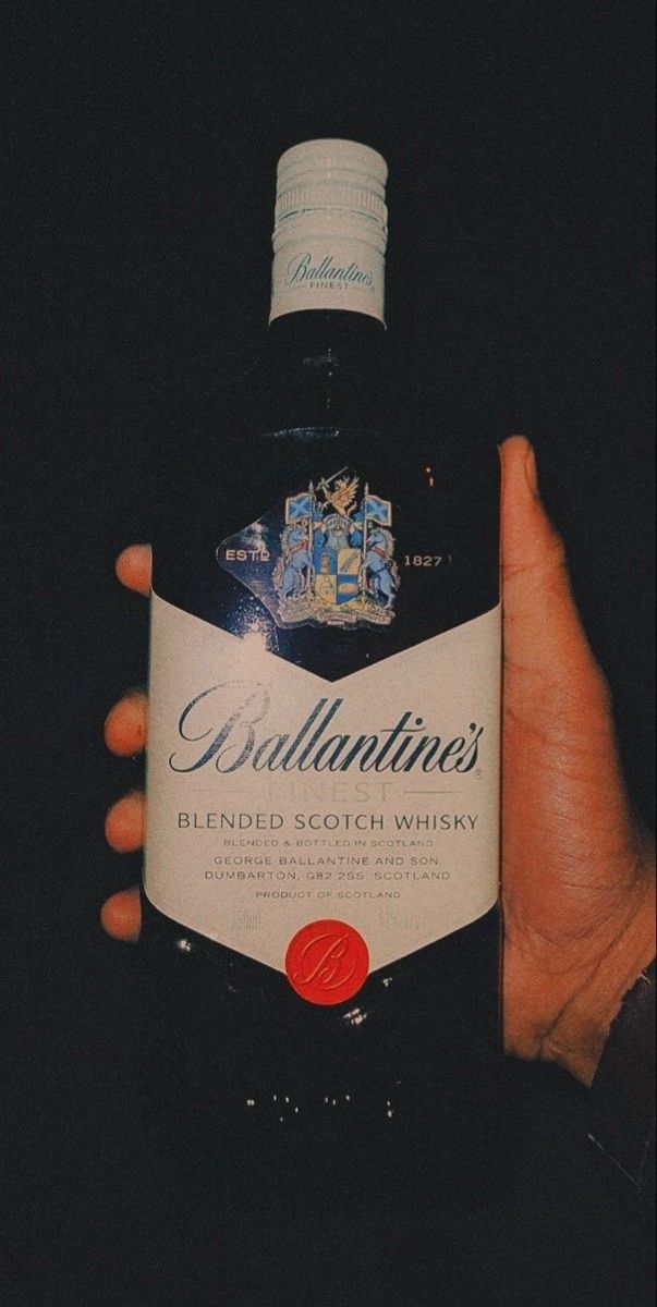 a person holding a bottle of alcohol in their hand with the caption ballantines blended scotch whisky