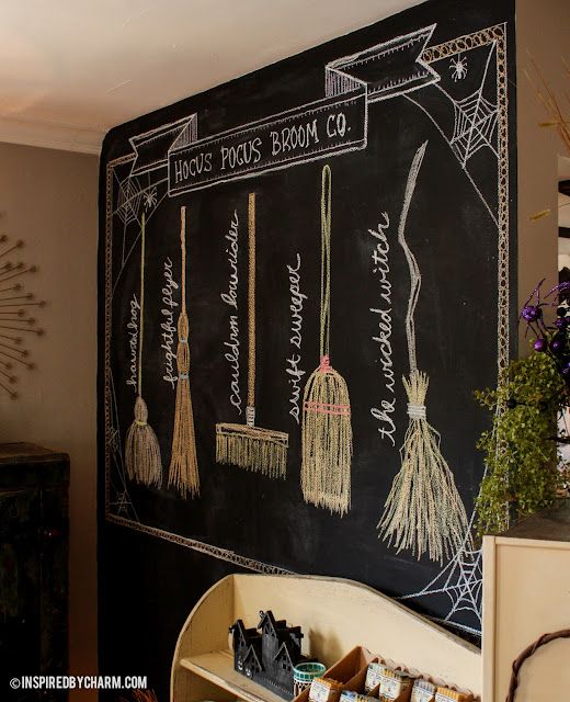 a chalkboard with brooms hanging from it's sides in front of a shelf