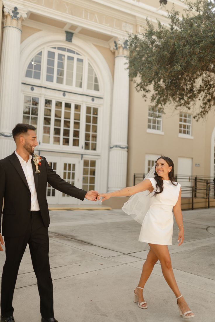 a man and woman holding hands in front of a building