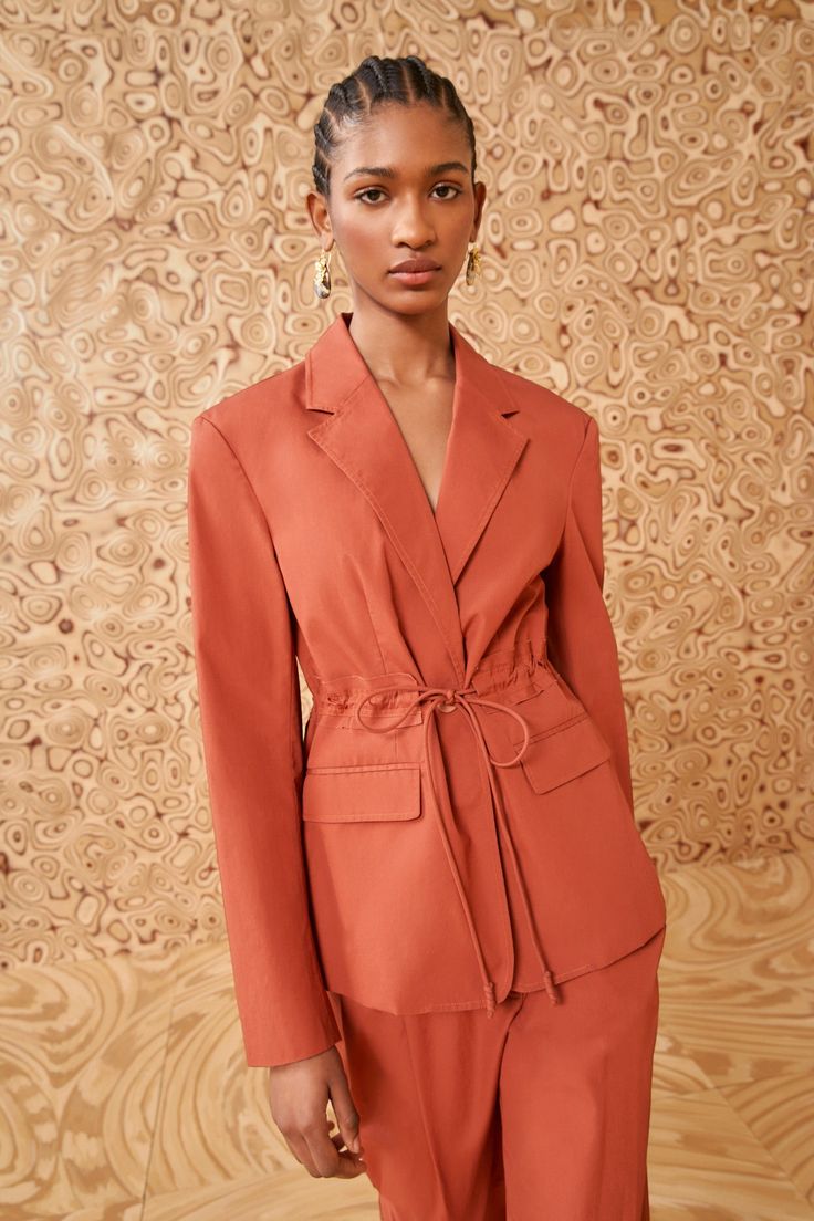 The Marisol Jacket is a versatile and sophisticated style crafted from premium cotton chino in a rich saffron orange. The tailored silhouette exudes timeless elegance, while the tie detail at the waist adds a contemporary and feminine touch. The lightweight and breathable cotton material ensures year-round wearability, making it a versatile piece that seamlessly transitions from season to season. Composition: 100% Cotton Pair with our Lani Pant and Floret Stone Drop Earring to complete the look. Formal Orange Outerwear With Notch Lapel, Formal Orange Notch Lapel Outerwear, Classic Orange Blazer For Workwear, Classic Orange Blazer For Work, Orange Notch Lapel Blazer For Work, Spring Blazer With Tie Waist And Notch Lapel, Fall Workwear Blazer With Tie Waist, Spring Formal Orange Outerwear, Orange Formal Outerwear For Spring