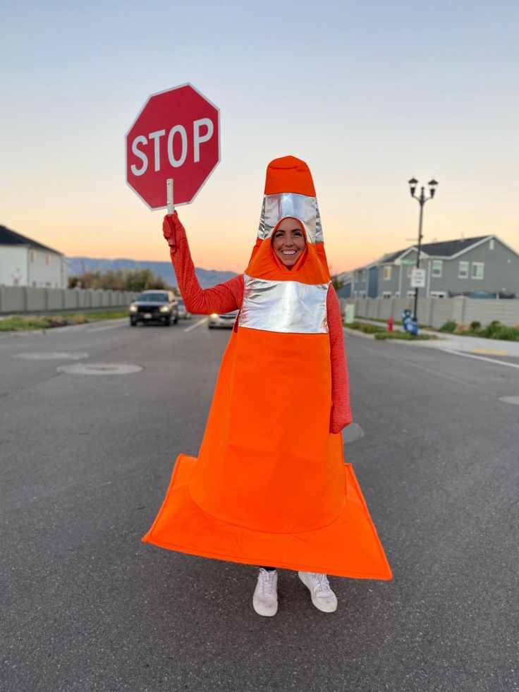 a woman in an orange dress is holding up a stop sign