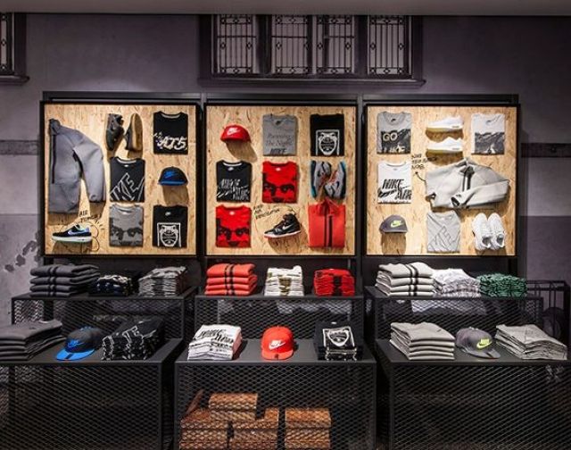 a display case filled with lots of different types of clothing and hats on wooden shelves