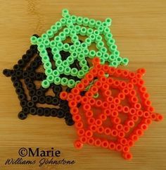 some beads are sitting on top of a wooden table and one is orange, the other is black