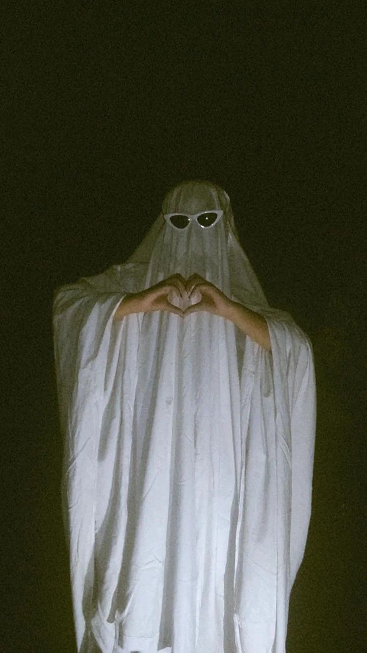 a person in a ghost costume holding their hands out to the camera