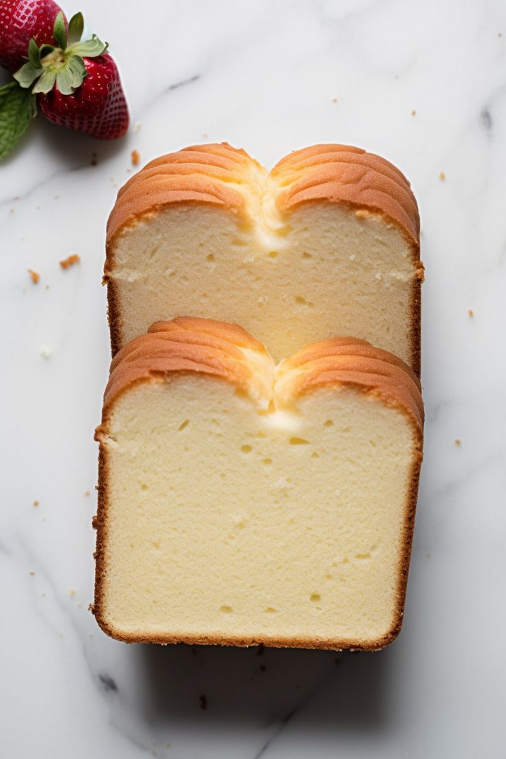 two slices of pound cake sitting on top of a counter next to some strawberries