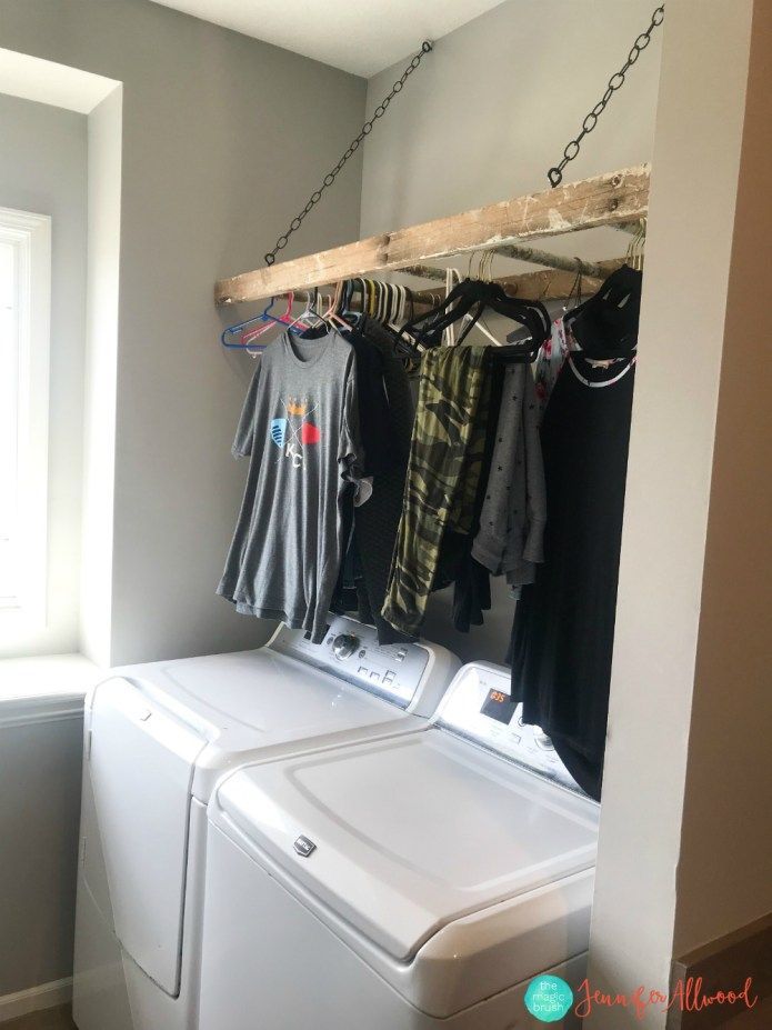 a washer and dryer in a laundry room with clothes hanging on the rack