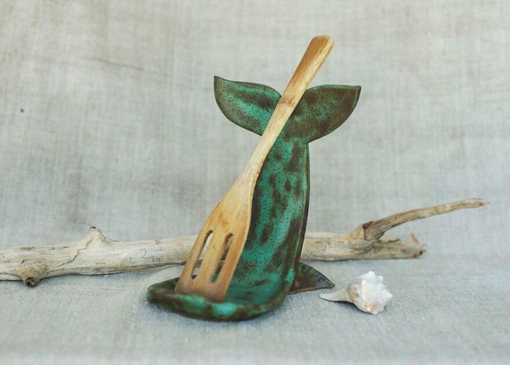 a wooden utensil holder sitting on top of a table next to a piece of driftwood