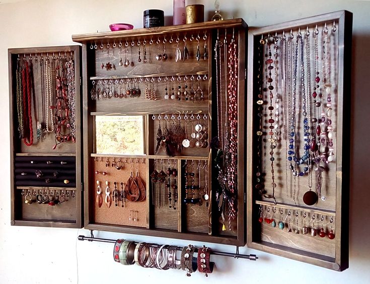 a wall mounted cabinet with jewelry hanging from it's sides