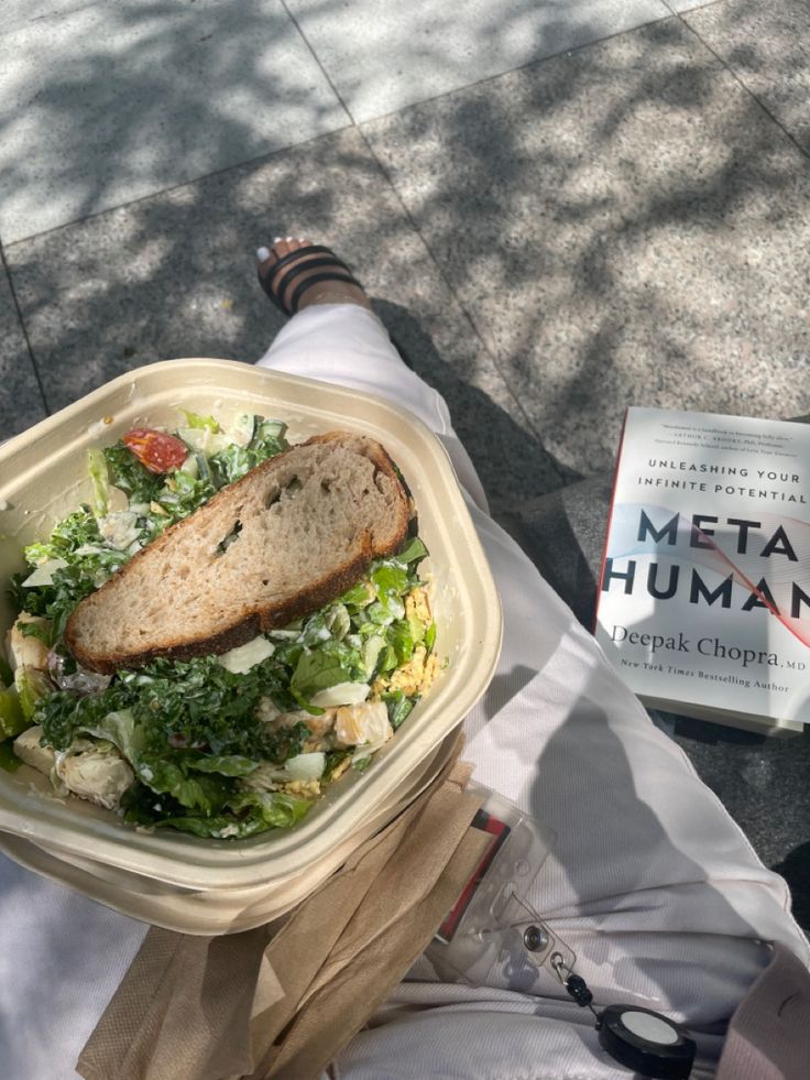 a person is holding a plastic container with food in it while sitting on the ground