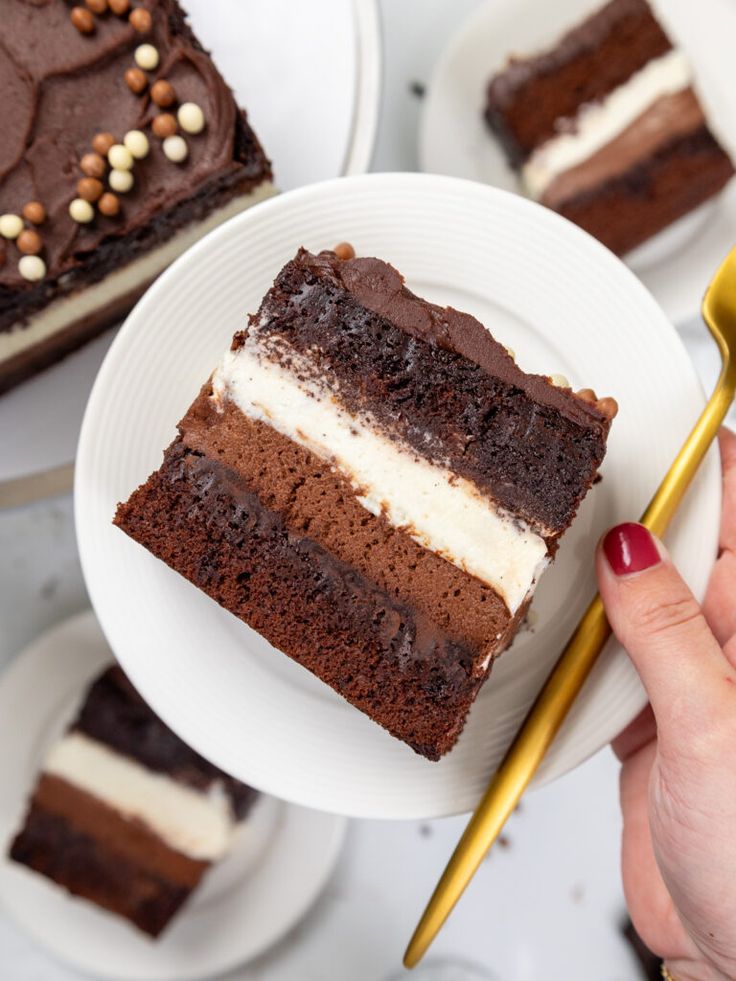 a piece of chocolate cake on a white plate with a gold serving spoon in front of it