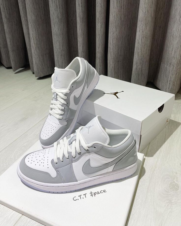 a pair of white and grey sneakers sitting on top of a box