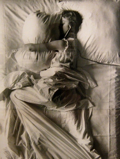 black and white photograph of a woman laying in bed with her head on the pillow