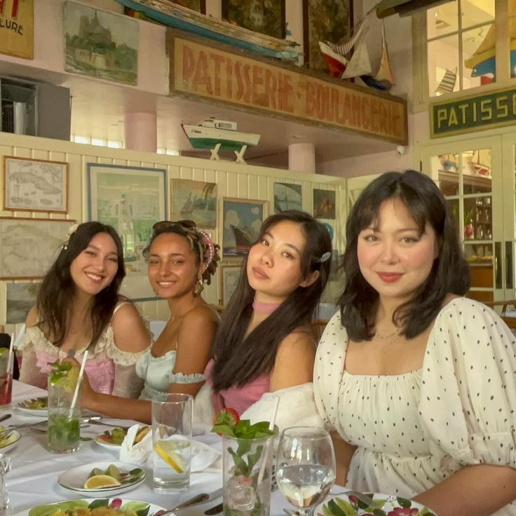 four women sitting at a table with plates of food