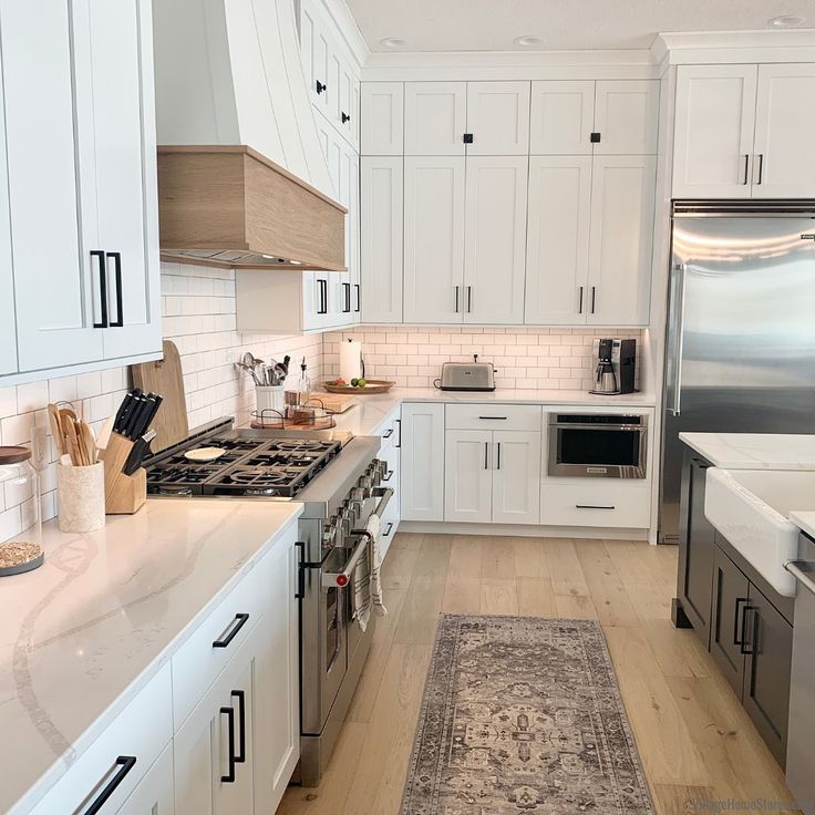 a kitchen with white cabinets and an area rug on the floor in front of the stove